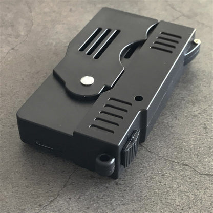 Rear angle of the folded stun gun with a small port on the edge, the ribbed switch and the lanyard hole on concrete