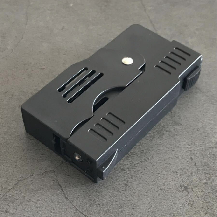 Folded stun gun seen from the side with the ribbed edge switch, ventilation slots and lanyard loop on concrete