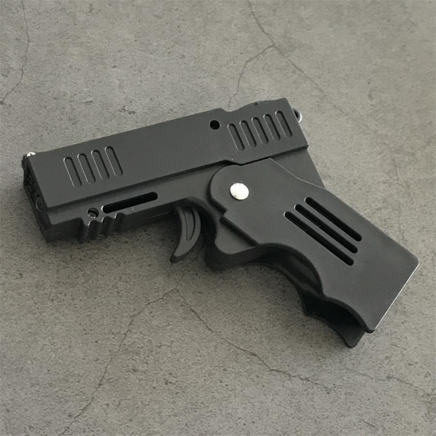 Front three-quarter view of the unfolded stun gun with the serrated muzzle end, trigger and hinge pin on concrete