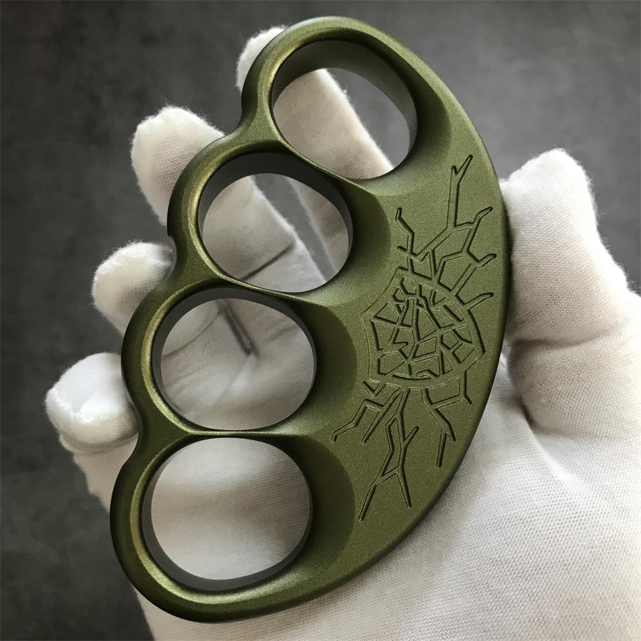 Front face of olive knuckle duster held upright in gloved palm
