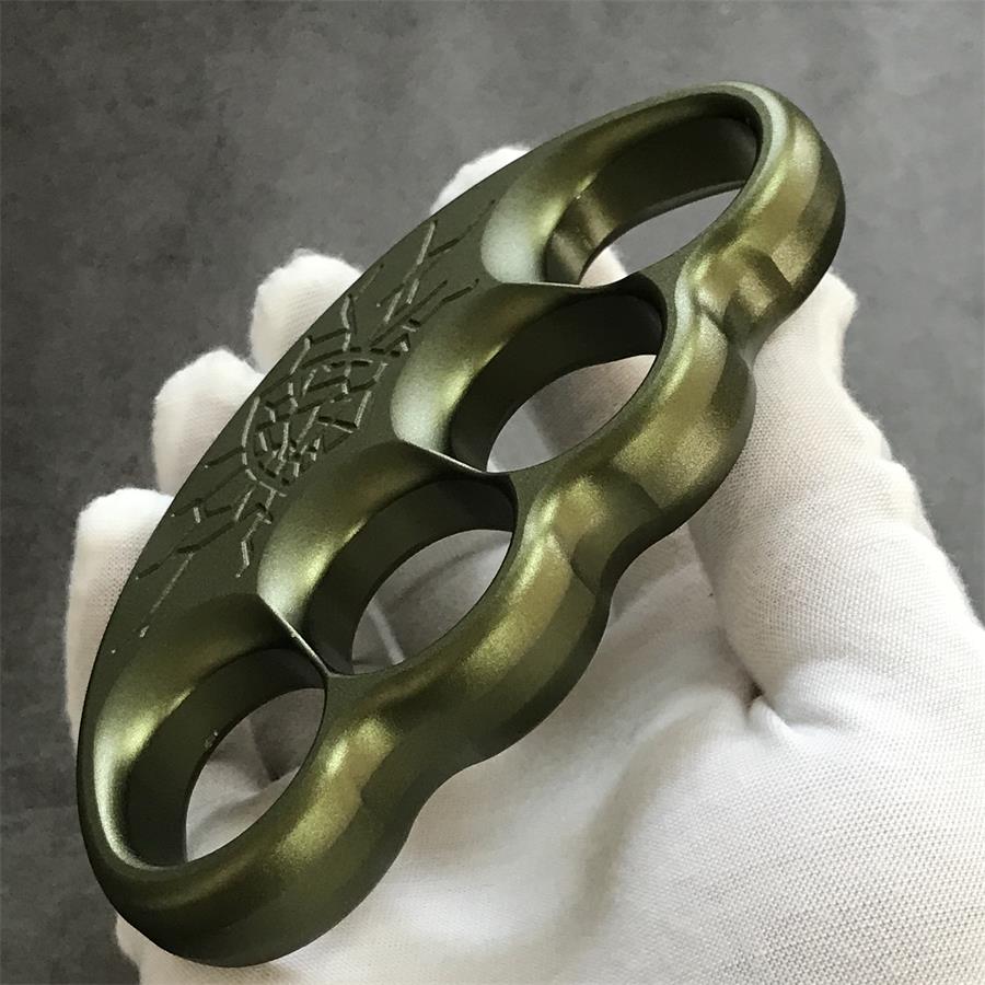 White gloved hand holding olive knuckle duster face forward