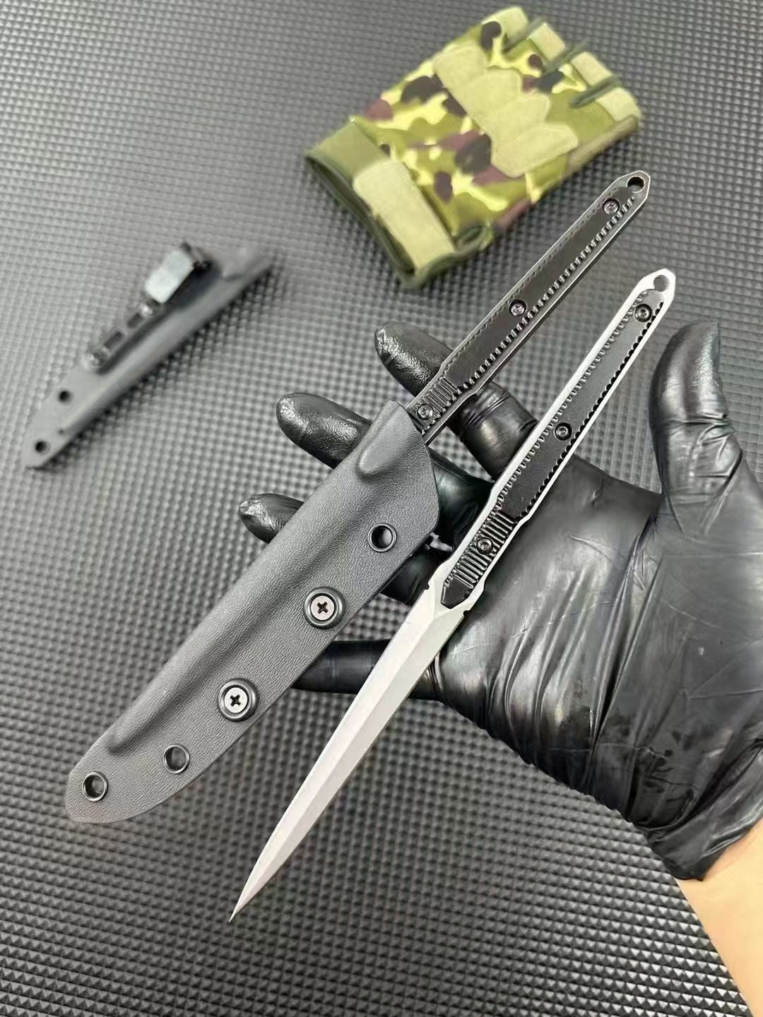 Gloved hand holding two bayonets with distressed and stonewashed blades