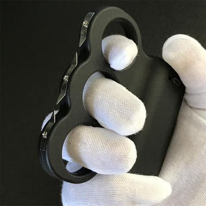 White-gloved hand holding the black three-hole stun device showing three serrated steel prong plates fixed with screws along the front edge