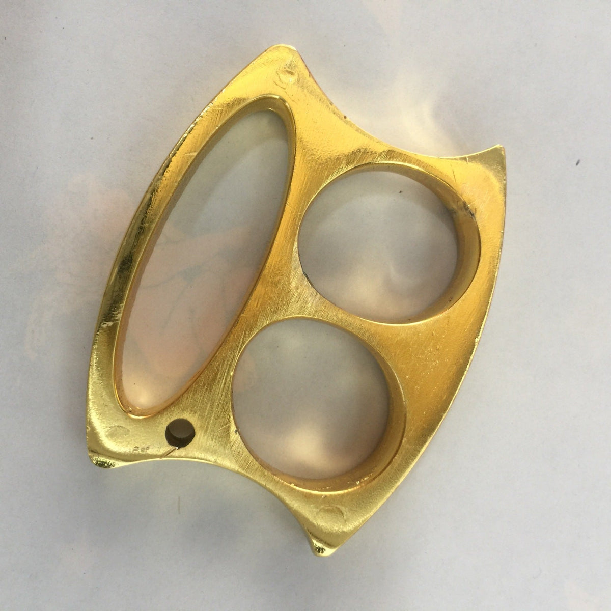 Golden two-hole zinc alloy knuckle duster laid flat on a plain white surface.