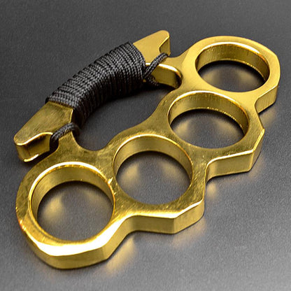 Golden-C aluminum knuckle duster with paracord on dark surface
