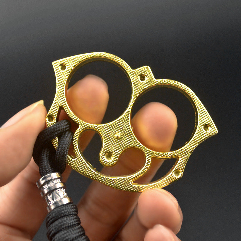 Golden sloth finger clasp held up with two fingers through the holes showing the grip and black paracord with silver bead