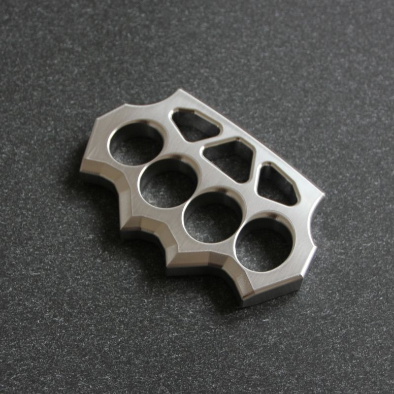 Flat lay angled view of the grass shaped stainless steel duster on dark textured surface.