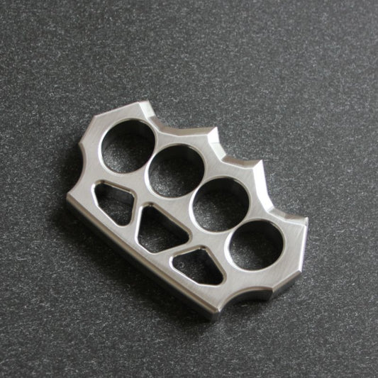 304 stainless steel grass shaped knuckle duster with four finger holes and decorative cutouts on a dark surface.