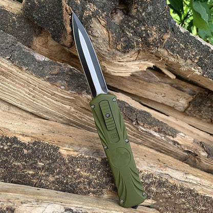 Green automatic OTF pocket knife standing on textured tree bark outdoors