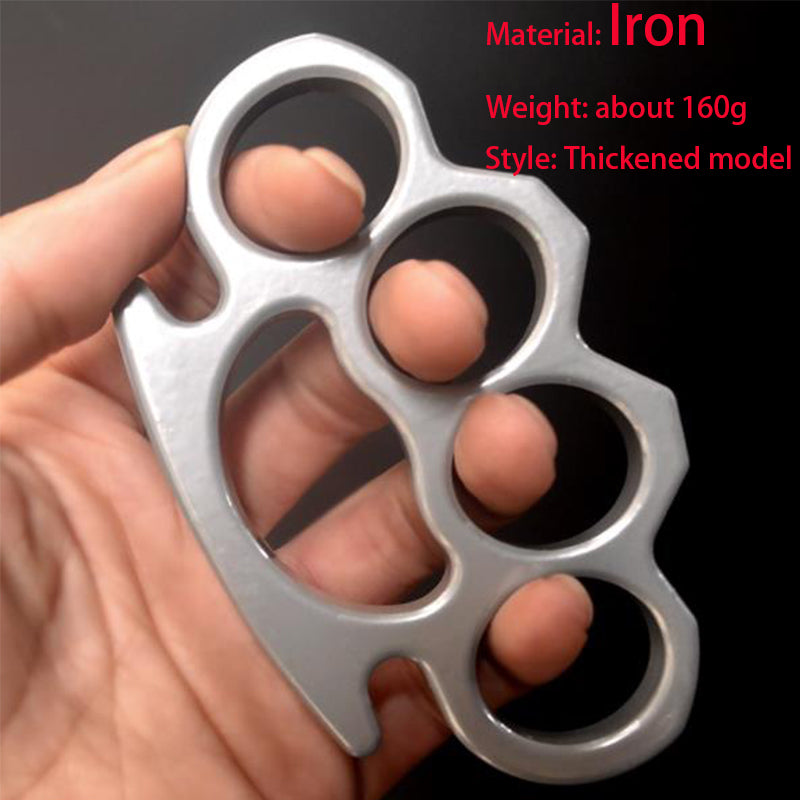 Silver thickened iron knuckle duster with four finger holes held up against a black background