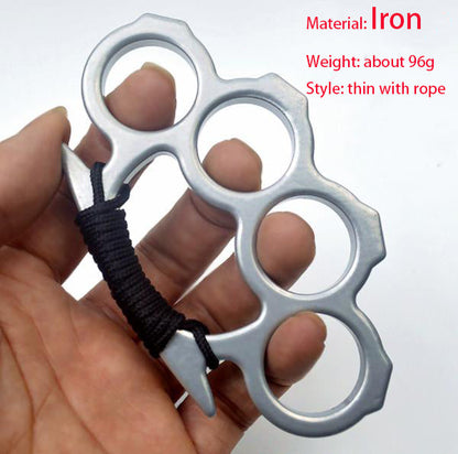 Silver thin iron knuckle duster with black rope wrapped around the handle, held up in an open hand
