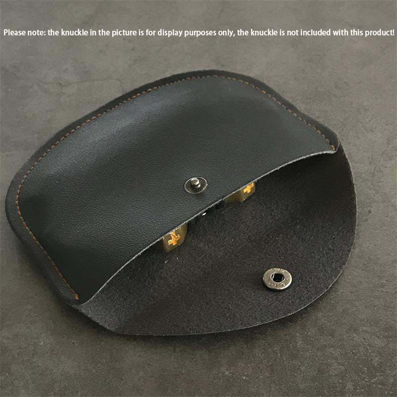 Black leather case half open on a gray surface, showing the suede lining and a metal snap stud