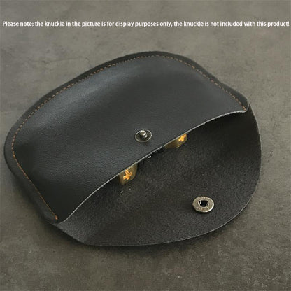 Black leather case half open on a gray surface, showing the suede lining and a metal snap stud