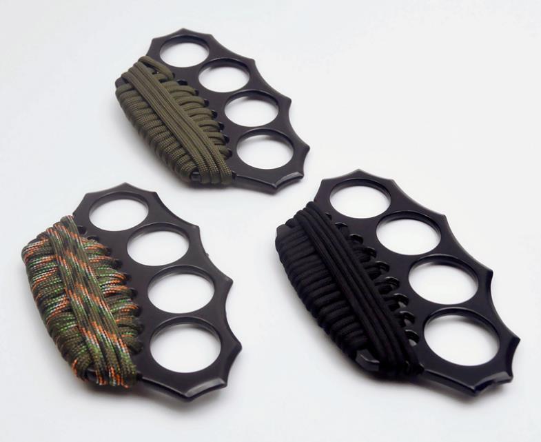 Three black knuckle dusters shown together on a white background, each with a different paracord in olive green, woodland camo, and black.