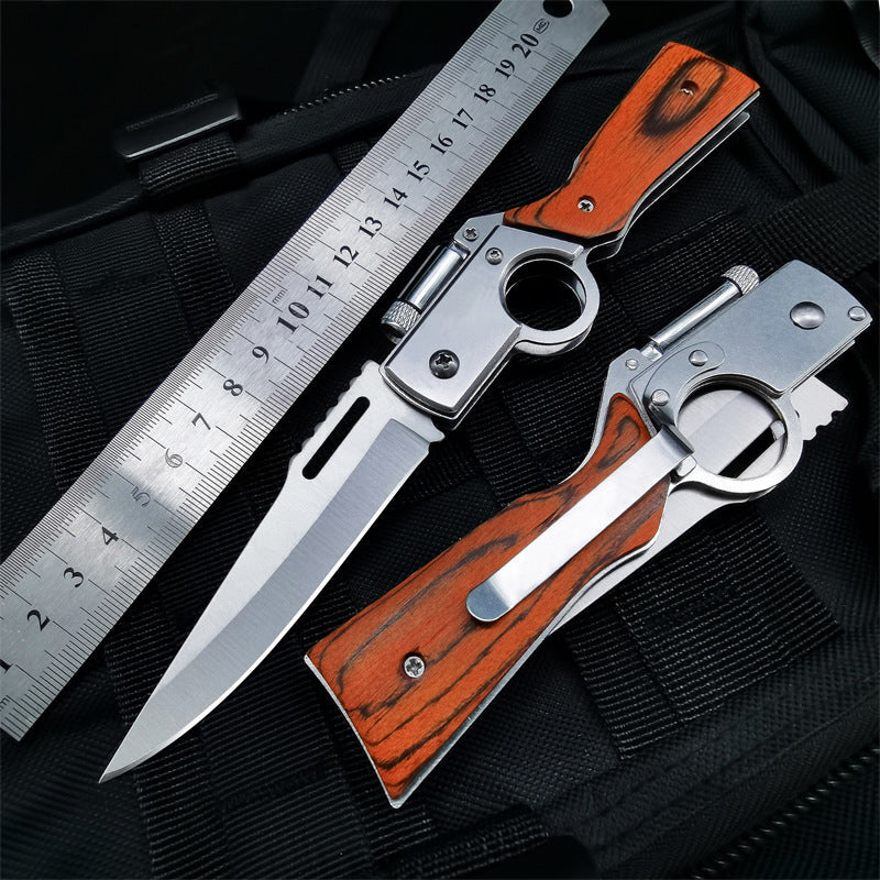 Large wood-handle folding knife open next to a metal ruler with closed version on black tactical fabric