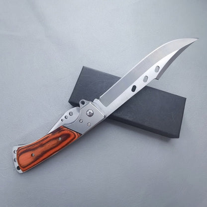 Large folding knife with redwood handle and silver bolsters resting on black box