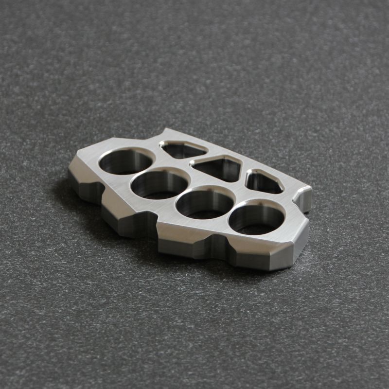 Flat lay view of the maple leaf shaped stainless steel duster on a dark textured background.