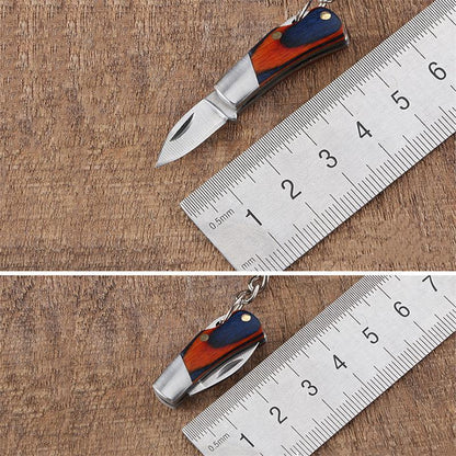 A two-panel size comparison of the mini folding knife beside a metal ruler - open at about 5 cm in the top panel and closed at about 3 cm in the bottom one, both with a navy-and-orange wood handle.