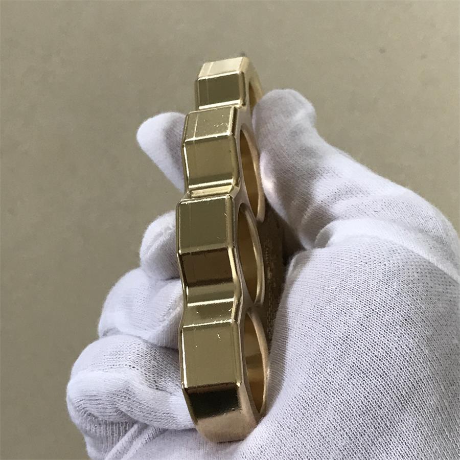 Close-up of the brass mini knuckle duster finger holes showing their depth and rounded stepped edges