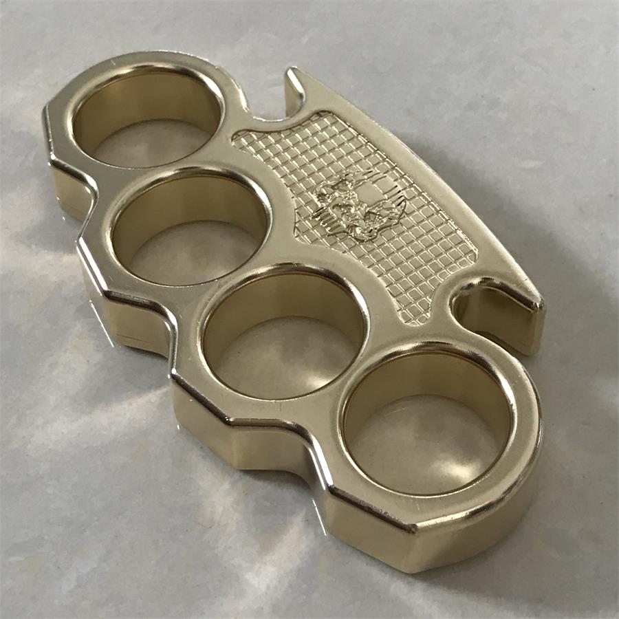 Detail view of the grid-textured skull panel and polished brass edge of the mini knuckle duster