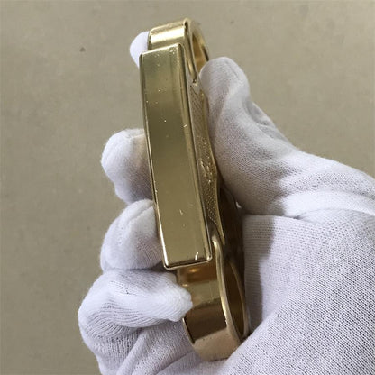 Side profile of the brass mini knuckle duster held vertically, showing its solid 14mm thickness
