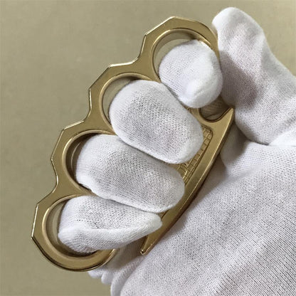 White-gloved fist worn through the four finger holes of the brass mini knuckle duster