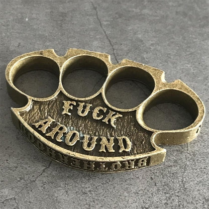 Antique copper retro knuckle duster close-up top view of four holes and raised lettering