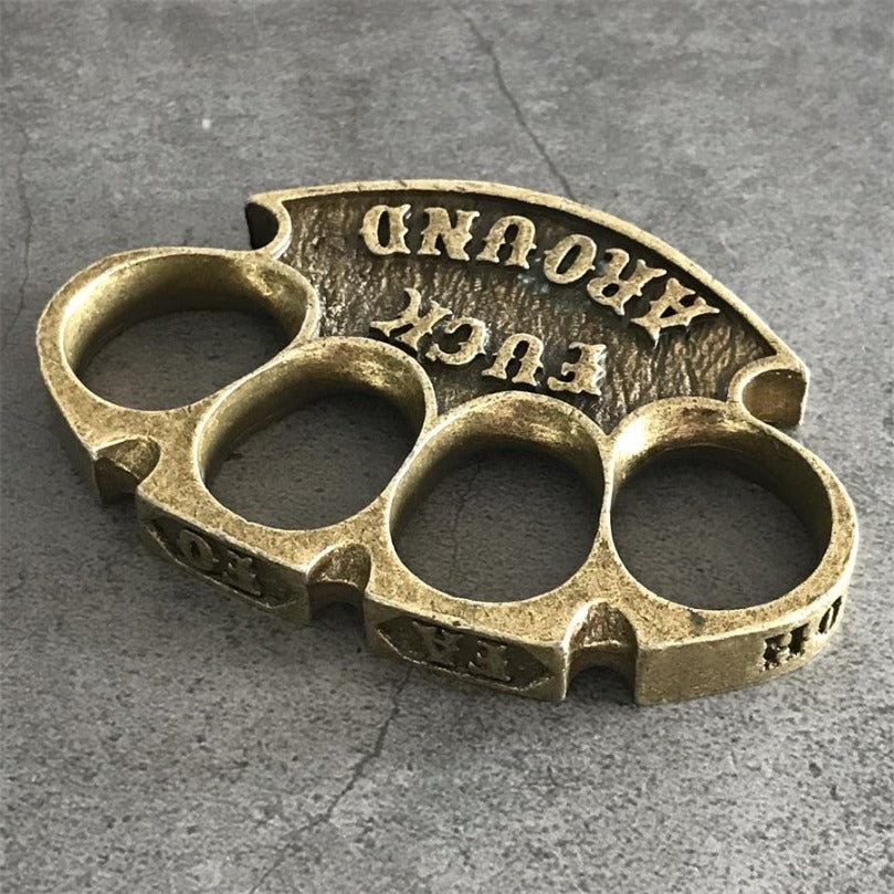 Antique copper retro knuckle duster lying flat on a grey cracked concrete surface
