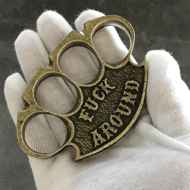Antique copper retro knuckle duster held palm-up in a white-gloved hand