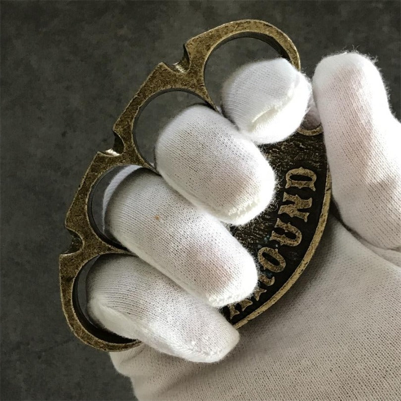 Antique copper retro knuckle duster in a gloved hand showing finger insertion from the side
