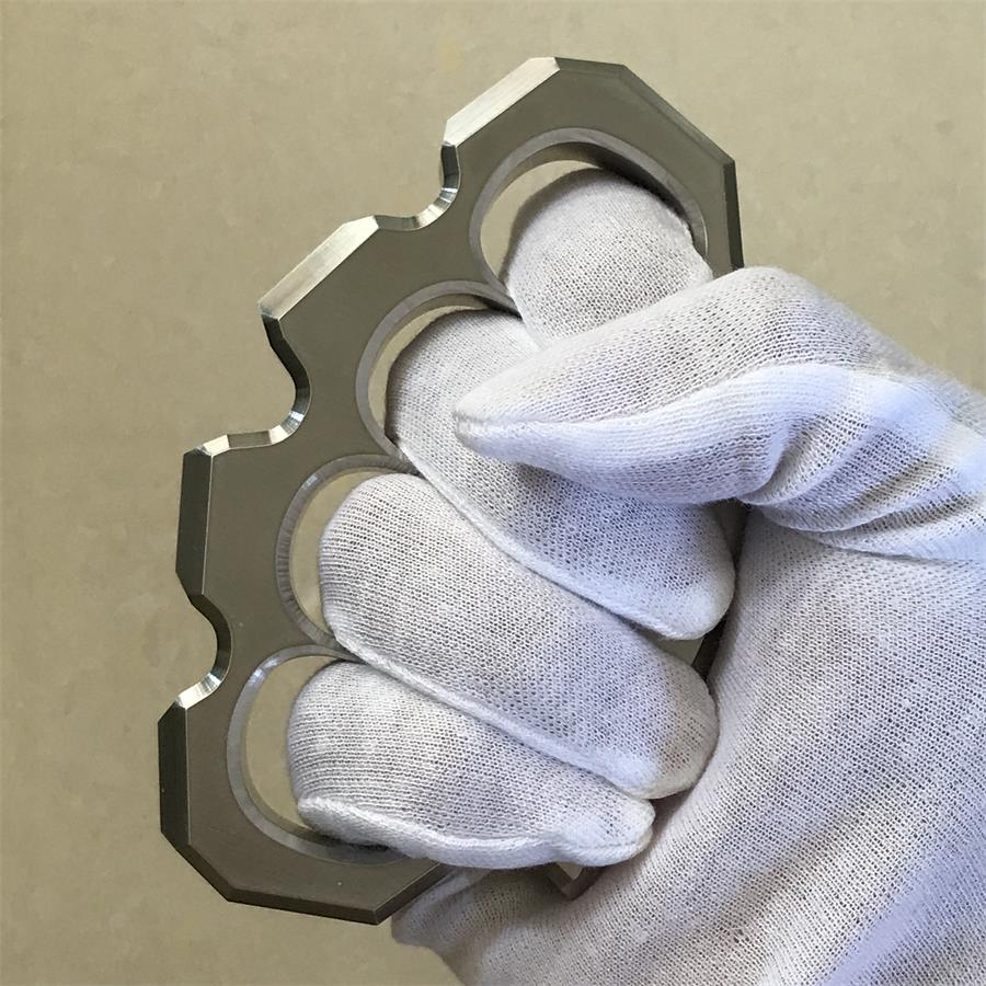 Close-up of the mirror polished four-hole duster held diagonally in a white-gloved hand.