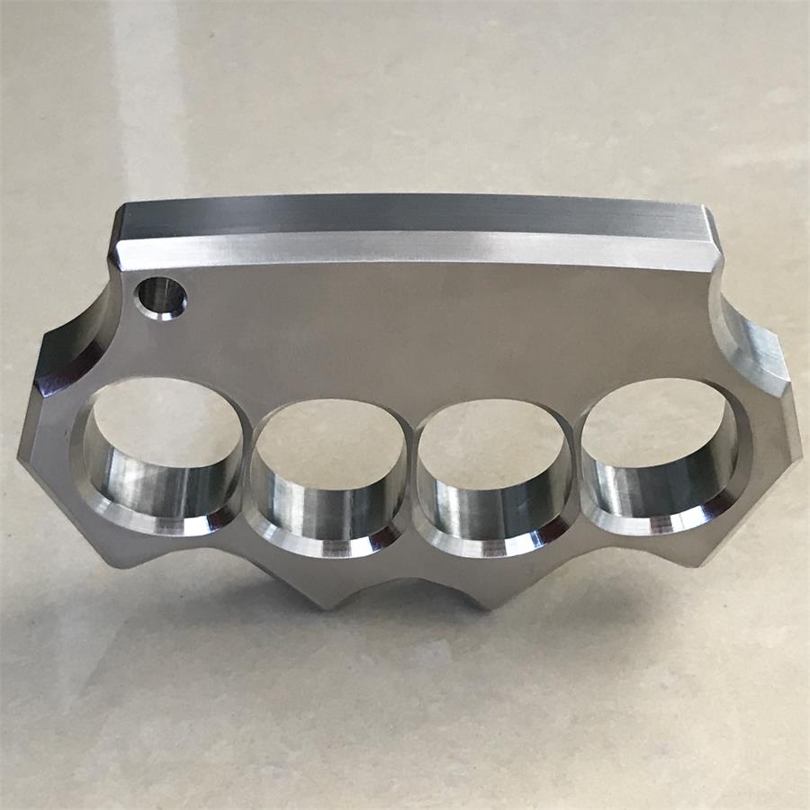 Another front edge view of the mirror polished four-hole stainless steel duster on beige surface.