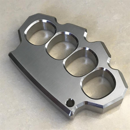 Mirror polished four-hole stainless steel duster lying flat on beige textured surface, full top view.