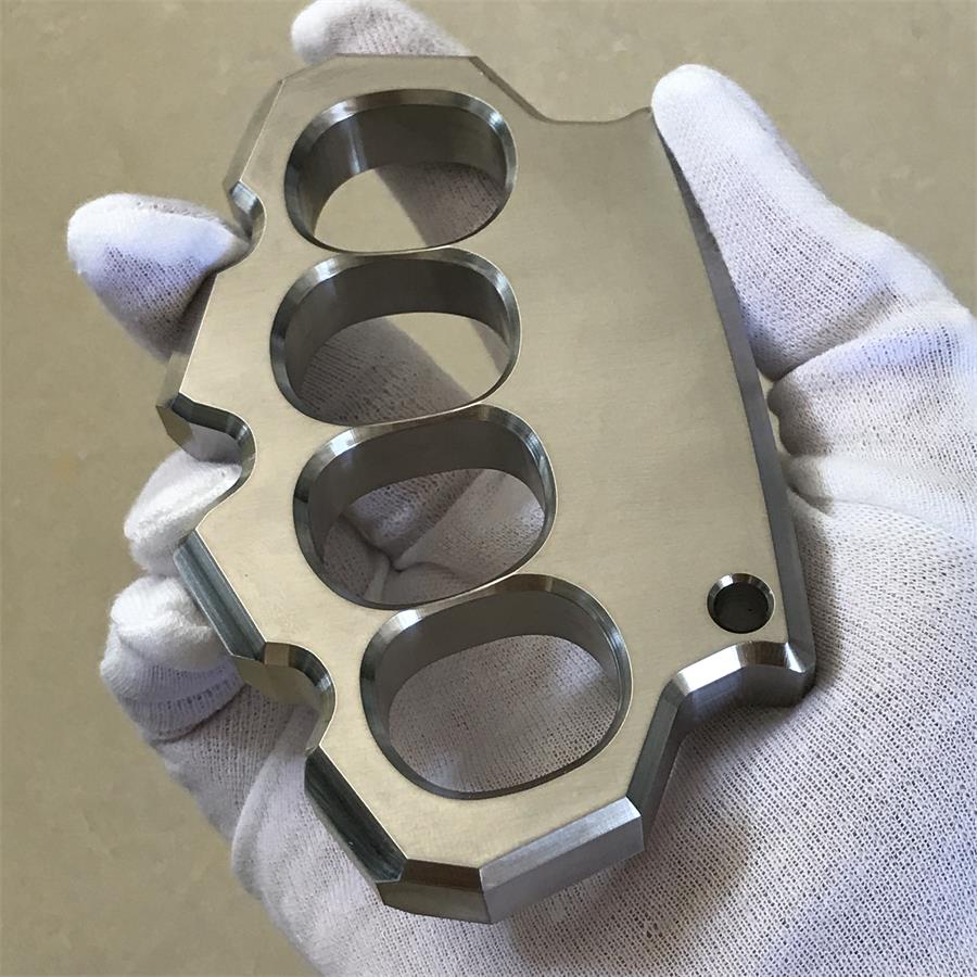 White-gloved hand holding the mirror polished four-hole duster at a slight angle, front view.