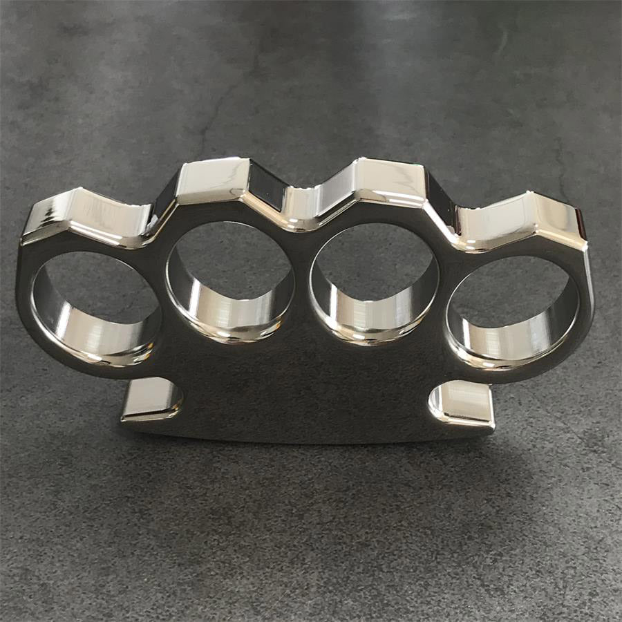 Angled view of the mirror-polished steel knuckle duster on a gray concrete surface, palm panel to the right