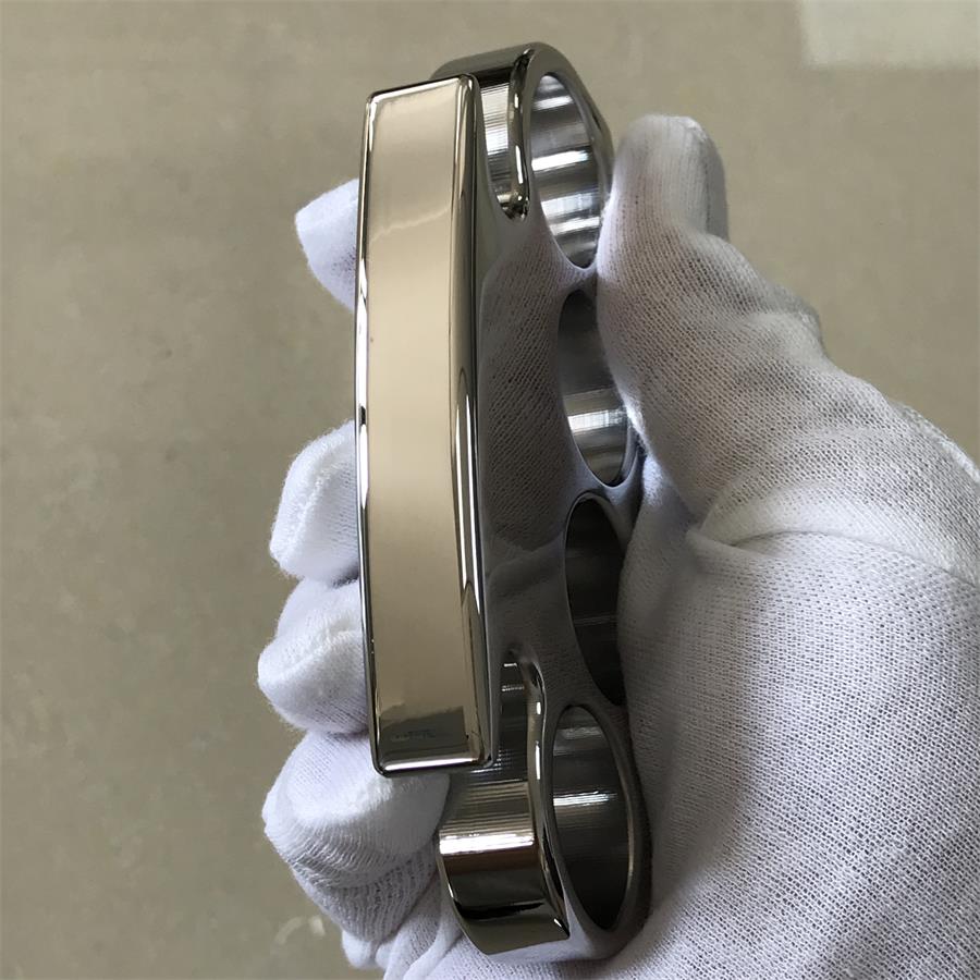 Angled gloved-hand view of the steel knuckle duster showing the four finger holes and the wide polished palm panel