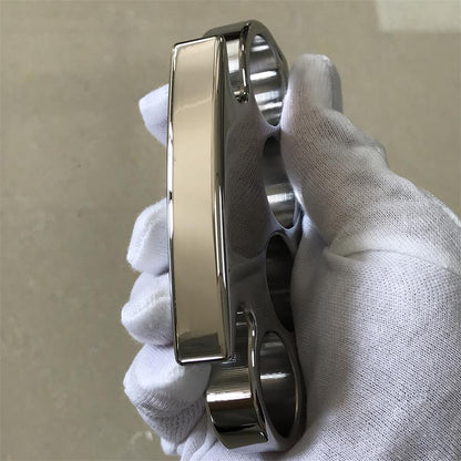 Angled gloved-hand view of the steel knuckle duster showing the four finger holes and the wide polished palm panel