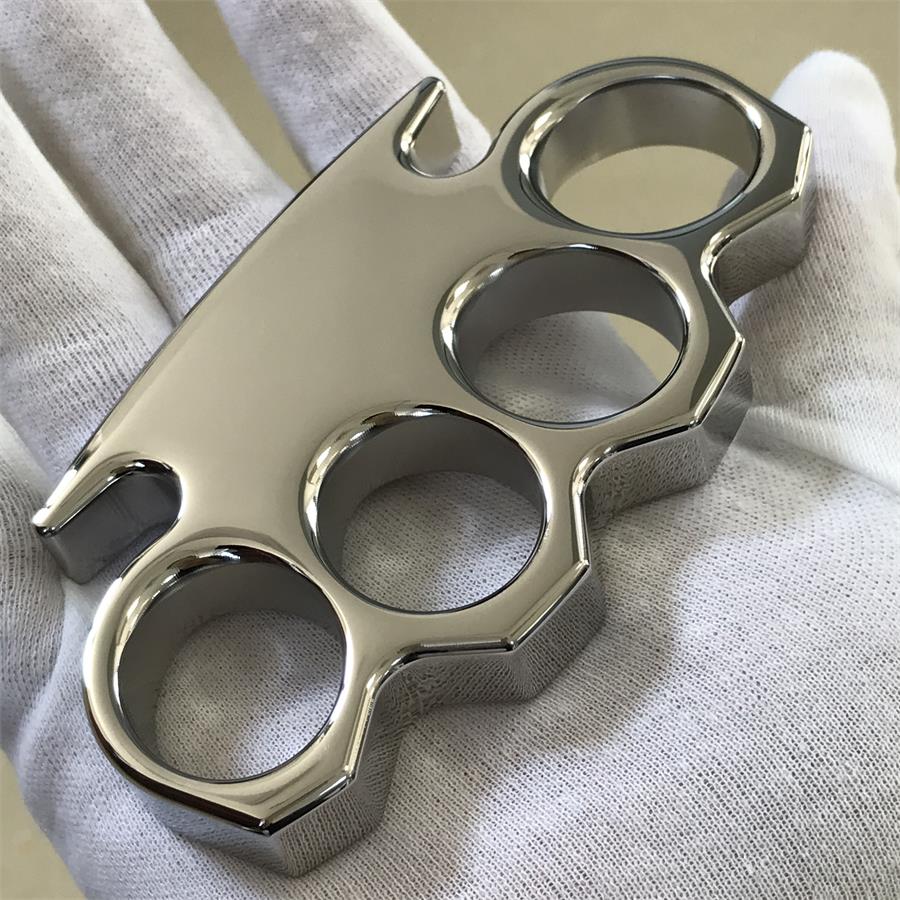 Face-down view of the mirror-polished steel knuckle duster on a printed sheet, showing the wide palm bar