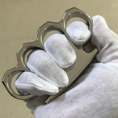 Two mirror-polished steel knuckle dusters laid side by side on a gray concrete surface