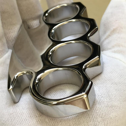 Side profile of the mirror-polished steel knuckle duster in a gloved hand, showing the palm bar thickness and brushed hole interiors