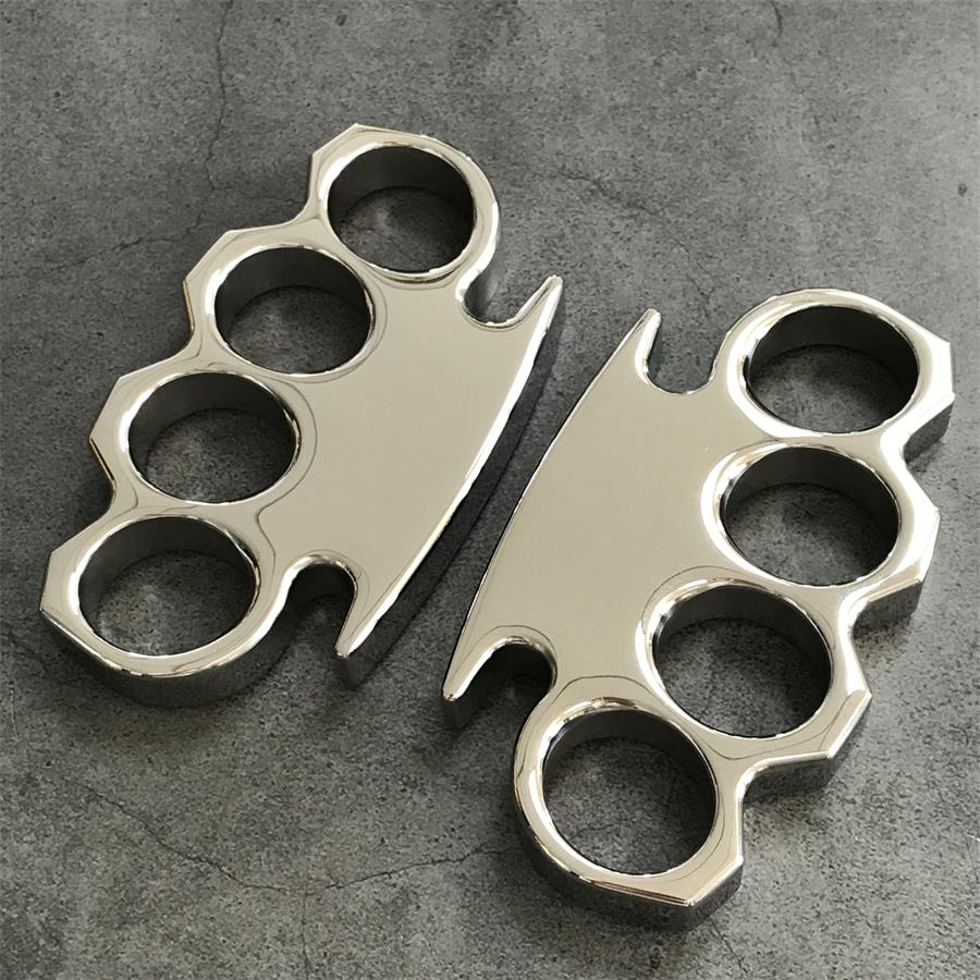 Front view of the steel knuckle duster standing on a dark stone surface, wide palm bar across the top