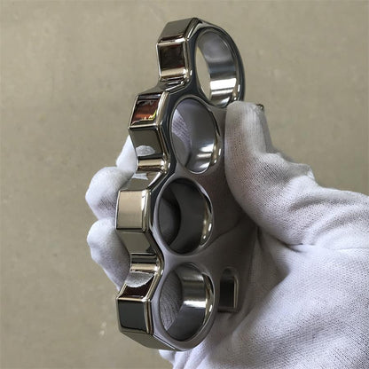 Vertical profile of the steel knuckle duster held in a gloved hand, showing the stepped knuckle edge and chamfered facets