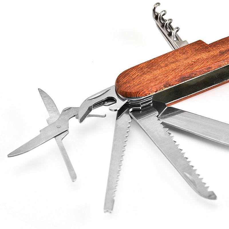 Close-up of the folding multi-tool open with scissors and two saw blades spread beside the corkscrew