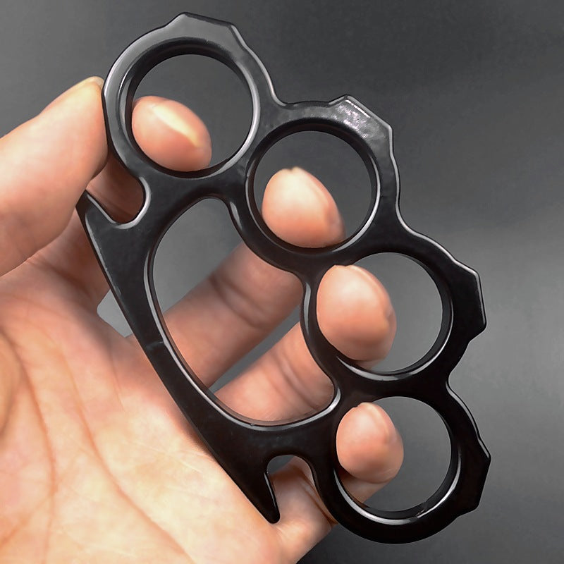Black outdoor knuckle duster held in hand showing grip and finger holes