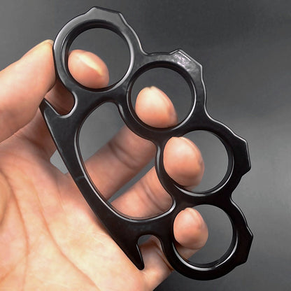 Black outdoor knuckle duster held in hand showing grip and finger holes