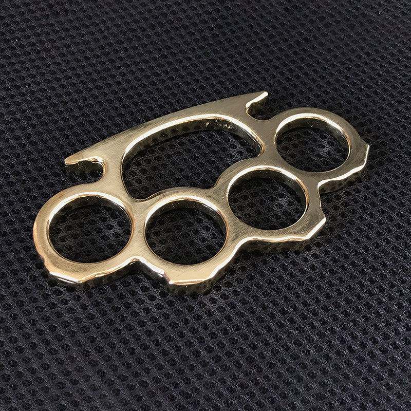Brass gold knuckle duster flat lay on black textured surface