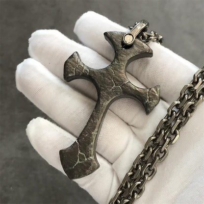 Obsidian finish TC21 titanium cross pendant in a white gloved hand with dark crackle surface