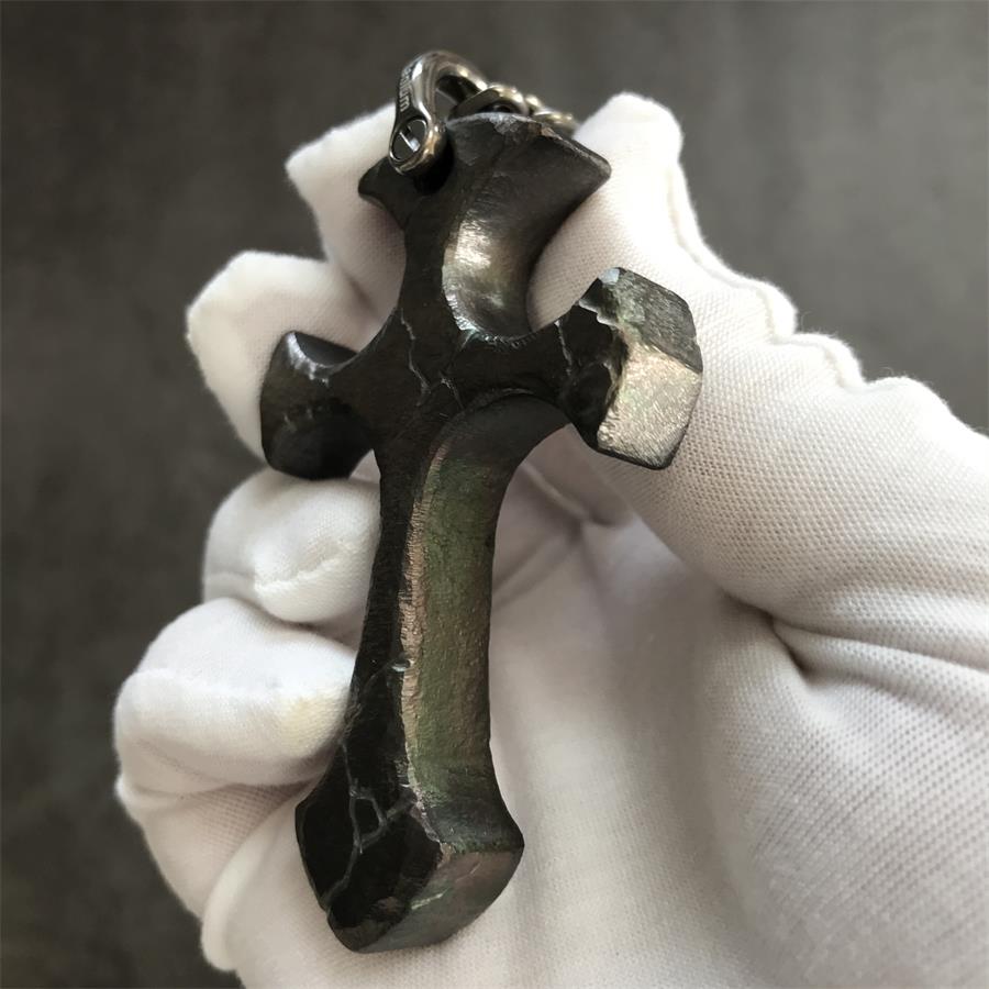 Side profile of Obsidian finish titanium cross pendant showing dark crackle texture and thickness