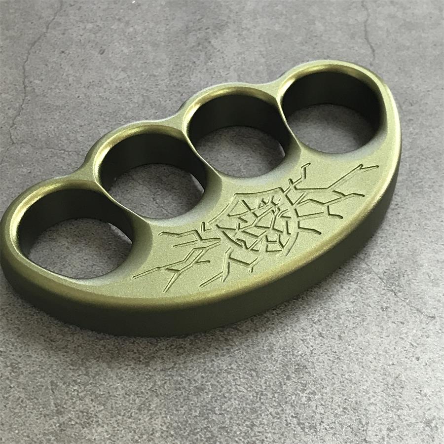 Olive aluminum knuckle duster with cracked crest engraving angled on grey stone