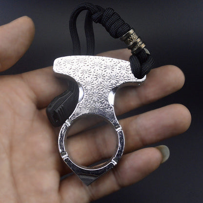 Full view of the silver single finger knuckle resting in an open palm showing the wide embossed plate, large finger hole and tapered point below